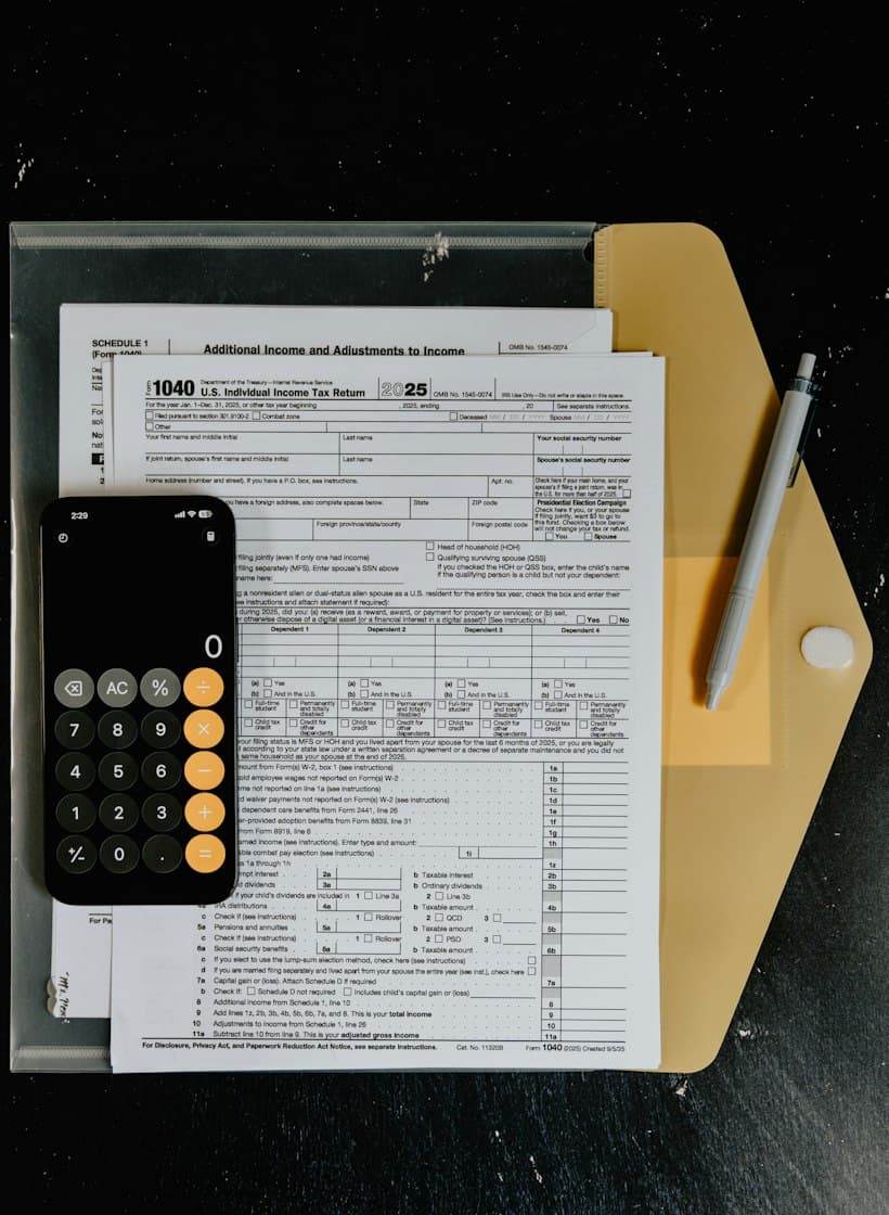 Tax forms laid out on a desk with a calculator and pen